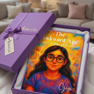 May include: A purple gift box with a matching ribbon and a tag labelled Infano.Care contains a book titled The Awkward Age: The Story of Every Adolescent Girl. The cover features a colourful illustration of a person with glasses and the name Gigi.