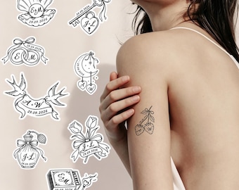May include: A collection of black and white temporary tattoo designs featuring various motifs including a seashell, a key with a heart lock, wedding rings, a crescent moon, birds with a banner, a perfume bottle, tulips, and a matchbox with a match.