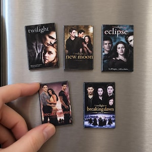 Op de afbeelding: Een set van vijf rechthoekige magneten met de filmposters van Twilight, New Moon, Eclipse, Breaking Dawn Part 1 en Breaking Dawn Part 2. Elke magneet toont de filmtitel en de hoofdrolspelers in hun respectievelijke filmscènes.