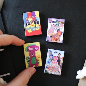 May include: Four miniature rectangular items featuring colourful graphic prints of children's television shows including The Wiggles, Doodlebops, Barney, and LazyTown. Each small rectangular piece displays the show's title and character imagery.