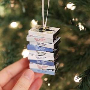 Peut inclure: Une décoration de sapin de Noël suspendue représentant une pile de neuf boîtiers DVD miniatures de la série The Office, saisons un à neuf. Chaque boîtier possède une tranche blanche avec le titre et le numéro de saison imprimés en couleurs.