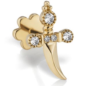 May include: A gold-toned stud earring shaped like a dagger with a curved blade. The hilt features four clear, round-cut stones set into the crossguard and pommel, with a flat, clover-shaped backing piece visible behind the main dagger design.