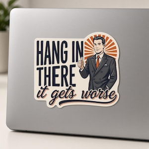 May include: A rectangular sticker featuring a man in a dark suit giving a thumbs up. The text reads HANG IN THERE it gets worse in dark blue and orange lettering against a cream background with an orange sunburst design behind the man.