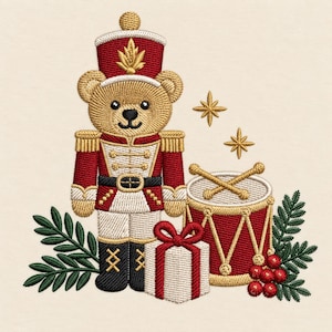 Puede incluir: Un diseño de bordado que muestra un oso de peluche color canela vestido de cascanueces con uniforme rojo y blanco con detalles dorados, junto a un tambor rojo con baquetas doradas, un regalo blanco con lazo rojo, ramas de pino y bayas rojas.