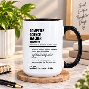 Könnte beinhalten: Ein weißer Keramikbecher mit schwarzem Henkel und schwarzem Innenrand. Der Becher ist mit schwarzem Text bedruckt, der einen Informatiklehrer als Code-Mentor definiert, inklusive Lautschrift und einer Liste beruflicher Aufgaben.