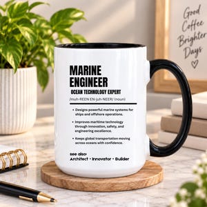 May include: A white ceramic mug with a black interior and handle, featuring black text that defines a Marine Engineer as an ocean technology expert, including bulleted job descriptions and the phrase see also: Architect, Innovator, Builder.