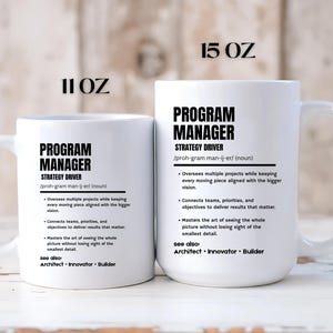 May include: Two white ceramic mugs with black text. The smaller mug is labeled 11 OZ and the larger mug is labeled 15 OZ. Both feature the definition of a Program Manager, including the text Strategy Driver, and see also: Architect, Innovator, Builder.