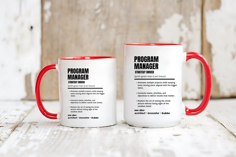 May include: Two white ceramic mugs with red interiors and handles. Each mug features black text defining a Program Manager as a strategy driver, including bullet points about overseeing projects, connecting teams, and mastering the big picture.