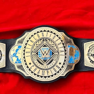 May include: A black leather championship belt featuring a large central gold plate with the text INTERCONTINENTAL CHAMPION and a globe design. Two smaller gold side plates feature the text NEVER GIVE UP HUSTLE LOYALTY RESPECT and JOHN CENA.