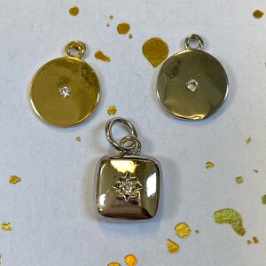 May include: Three silver and gold charms with small clear rhinestones. The charms are a round disc, a square, and another round disc.