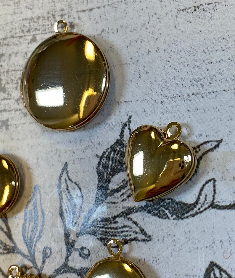 May include: Two gold-tone metal charms, one round and one heart-shaped. Both charms have a loop for attaching to a necklace or bracelet.