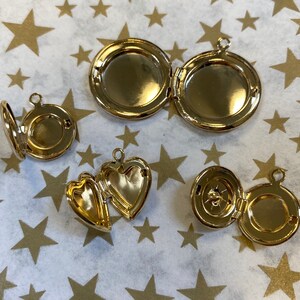 May include: Four gold-toned locket necklaces with different designs. The lockets are open to reveal the inside.