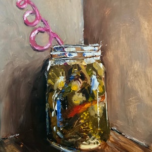 Op de afbeelding: Een glazen pot gevuld met een mengsel van groene, gele en rode items, met een roze rietje dat uit de bovenkant steekt. De pot staat op een houten oppervlak.