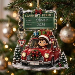 May include: A Christmas tree ornament featuring a red car with a character wearing a Santa hat, topped with a sign reading LEARNER'S PERMIT, NAME: Oliver, DATE: 2026. The car has a wreath on the grille, a NEW DRIVER sign, and a license plate reading NEW ADVENTURES.