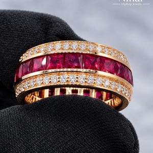 Könnte beinhalten: Ein goldener Bandring mit einer mittleren Reihe aus quadratisch geschliffenen roten Rubinen, flankiert von zwei Reihen kleiner runder weißer Diamanten. Der Text Nihar Hiphop Jewels steht in der oberen rechten Ecke.