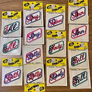 May include: A collection of vintage Show Offs embroidered name patches on yellow cardboard backing. Each rectangular patch features a name in cursive script, including Al, Amy, Andrea, Ann, Betty, Bill, Beth, and Beverly, with checkered or heart accents.