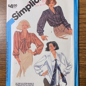 May include: A Simplicity sewing pattern envelope 6599 for miss sizes 12, 14, and 16. The front features illustrations of three long-sleeved blouses with collars and tie-front details, shown in dark striped, solid copper, and white fabric variations.