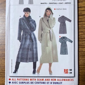 May include: A sewing pattern envelope for a coat, featuring two style variations: a dark grey plaid coat with a collar and a light beige hooded coat with a tie belt. The package includes text labels for sizes 12 through 24 and sewing instructions.