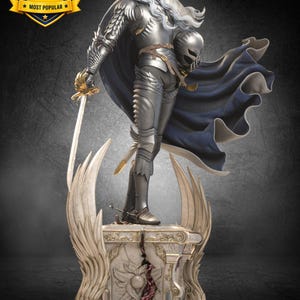 May include: A detailed figurine of a long-haired white-haired warrior in silver plate armor, holding a sword and a helmet. The figure wears a flowing dark blue cape and stands on an ornate, winged stone pedestal with a central cracked relief.