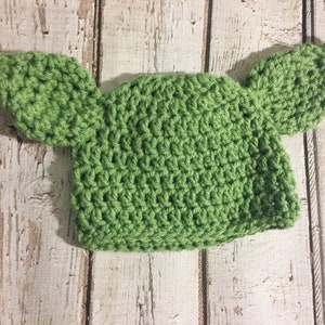 Puede incluir: Sombrero de ganchillo verde con dos orejas grandes, que se asemeja a un personaje ficticio popular.