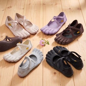 May include: A collection of Vibram five-toe shoes in various colors including light pink, lavender, brown, white, grey, and black. Each shoe features individual toe compartments, a cross-strap closure, and a yellow Vibram logo on the sole.