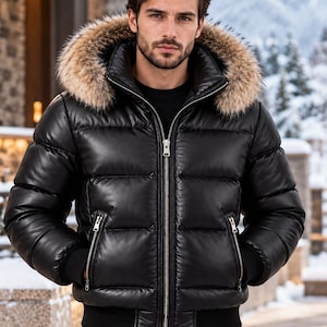 May include: A black puffer jacket featuring a smooth, water-resistant finish, a full-length silver front zipper, and two zippered side pockets. The jacket includes a hood trimmed with thick, brown faux fur and black ribbed cuffs.