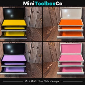 May include: Four small metal tool chests with open lids and drawers, featuring MiniToolboxCo branding. The chests have black or white exteriors with bright matte liners in yellow, orange, lavender, and pink. Each unit has a hinged lid.