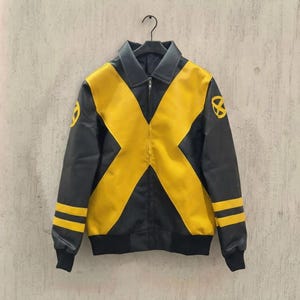May include: A black and yellow jacket featuring a large yellow X pattern across the front, a collared neckline, a central zipper closure, and two yellow stripes on each sleeve. The shoulders display a circular yellow emblem on each side.