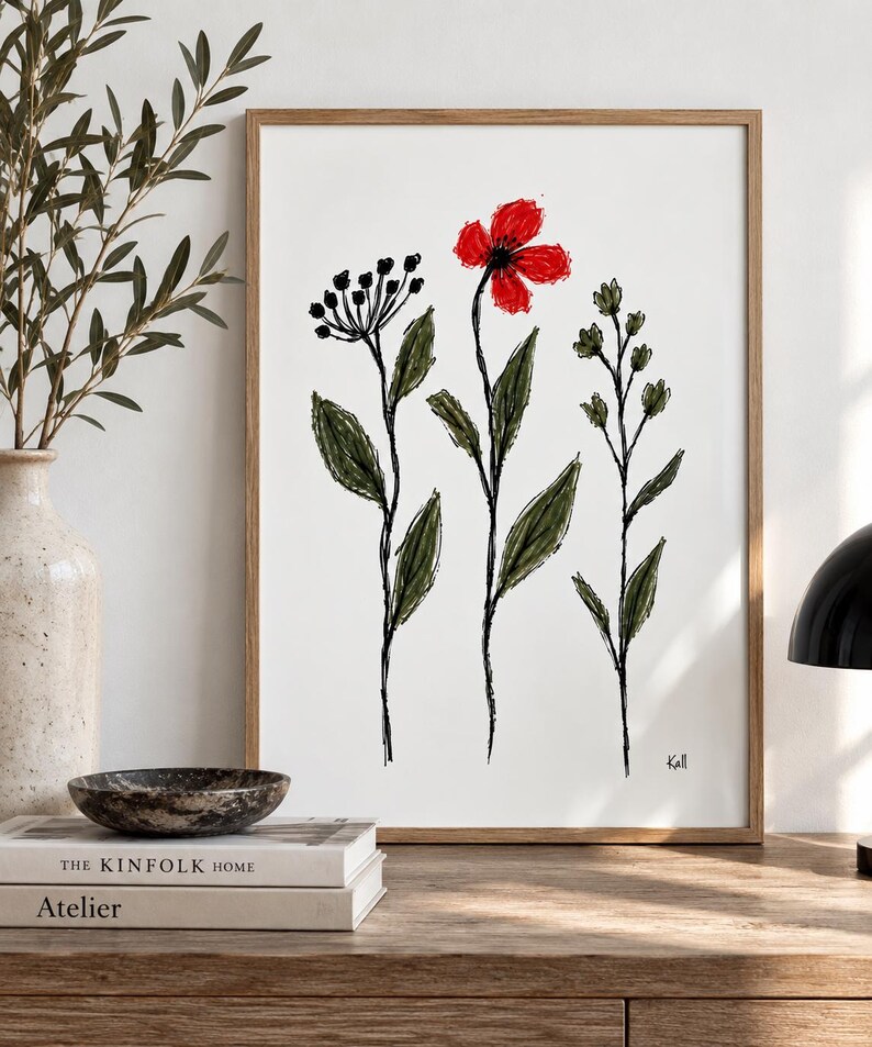 May include: A framed wall art print featuring a sketch-style illustration of three wildflowers on a white background. The central flower has bright red petals, while the surrounding stems and leaves are rendered in dark green and black ink lines.