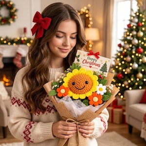 May include: A crochet flower bouquet featuring a large yellow sunflower with a smiling face, smaller orange and white flowers, and green leaves, wrapped in brown paper with a card that reads Happy Christmas and a small red bow.