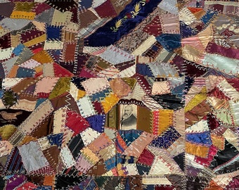 Pode incluir: Uma colcha vintage de patchwork feita com uma variedade de tecidos em tons de marrom, azul, vermelho e verde. A colcha é composta por muitas peças de tecido de diferentes formas e tamanhos, e é costurada com uma variedade de pontos diferentes. A colcha é um belo exemplo de acolchoado tradicional americano.