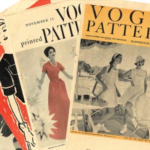 May include: A stack of vintage Vogue Pattern magazines. The covers feature illustrations of women in dresses and text including "Vogue Pattern" and dates like "November 15" and "June". The magazines have a retro aesthetic.