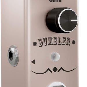 May include: A light beige guitar effects pedal with a metallic finish, featuring three small black control knobs labeled Volume, Voice, and Tone, a large central Gain knob, and a silver footswitch. The text DUMBLER and iSET are printed on the front.