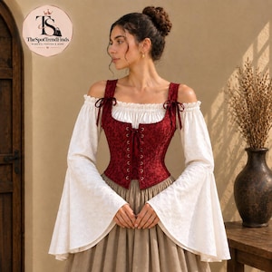 May include: A long-sleeved off-the-shoulder top featuring a white base with a subtle tonal pattern and wide bell sleeves. The garment includes a deep red corset-style bodice with a floral pattern, front lace-up detailing, and shoulder ties.