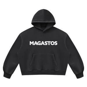 May include: A black hooded sweatshirt featuring the word MAGASTOS printed in bold white capital letters across the chest. The garment includes a front kangaroo pocket, long sleeves with ribbed cuffs, and a matching black hood with a drawstring-free design.