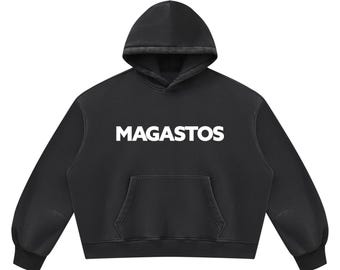May include: A black hooded sweatshirt featuring the word MAGASTOS printed in bold white capital letters across the chest. The garment includes a front kangaroo pocket, long sleeves with ribbed cuffs, and a matching black hood with a drawstring-free design.