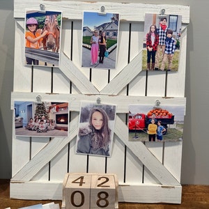 May include: White wooden photo display with five pictures of children. The pictures are held in place with clips. The display is on a table with a wooden block calendar that reads "42 08".