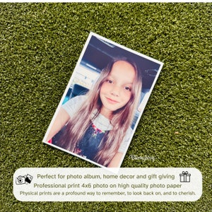May include: A 4x6 inch photograph of a young girl with long brown hair, wearing a floral print dress, smiling at the camera. The photo is printed on high quality photo paper.