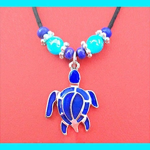 May include: A blue and turquoise beaded necklace with a blue enamel turtle pendant. The necklace is made of black cord and has a silver clasp.