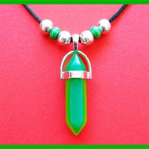 Op de afbeelding: Een ketting met een groene kristallen hanger, een zilveren setting en een zwart koord. De hanger is puntvormig en heeft een groene en lichtgroene kleur.