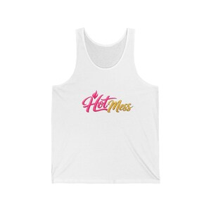 May include: A white sleeveless tank top featuring the text Hot Mess printed in the centre. The word Hot is written in a stylised pink script font with a small flame icon above the letter H, while the word Mess is in a gold glittery script font.