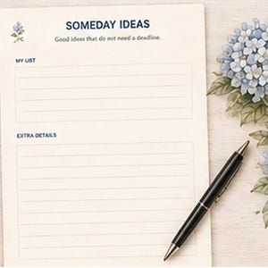 May include: A cream-colored notepad with blue text reading SOMEDAY IDEAS, Good ideas that do not need a deadline, MY LIST, and EXTRA DETAILS. The page features blue hydrangea illustrations and is accompanied by a black ballpoint pen.