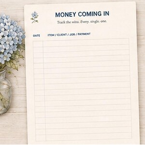 May include: A cream-colored paper tracker sheet with the text MONEY COMING IN and Track the wins. Every. single. one. The sheet features columns for DATE and ITEM / CLIENT / JOB / PAYMENT, decorated with a small blue floral illustration.