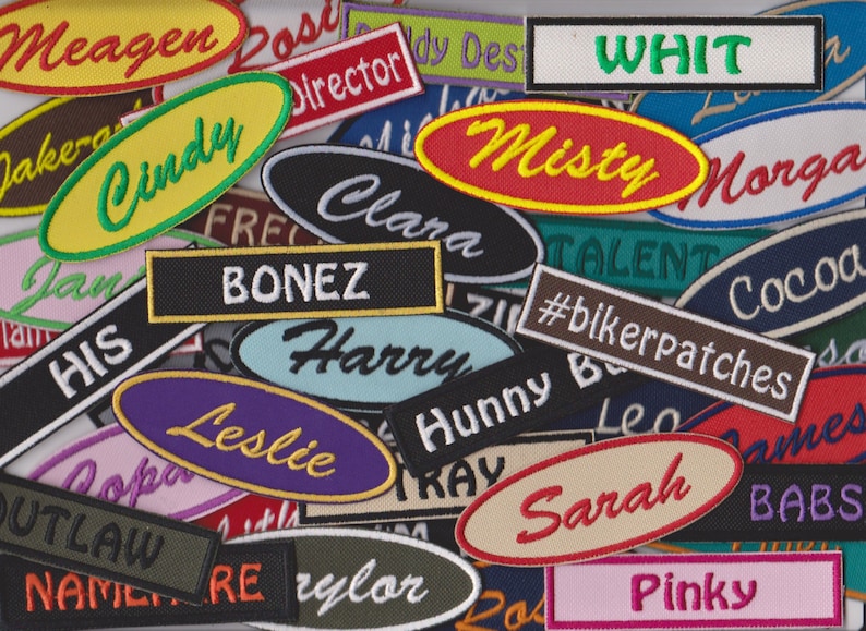 May include: A collection of colourful embroidered patches with names such as Meagen, Cindy, Misty, Whit, Harry, Leslie, Sarah, and Pinky. The patches are various shapes and sizes, including ovals, rectangles, and squares.  The patches are made of fabric and have a stitched border.