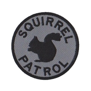 May include: A gray and black embroidered patch with the text "Squirrel Patrol" and a silhouette of a squirrel.