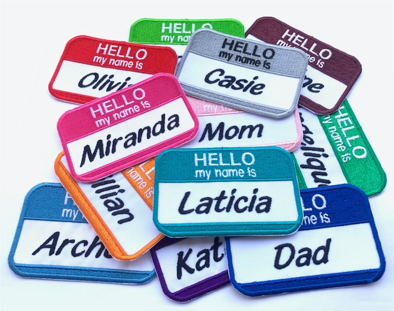 May include: A collection of colorful iron-on name patches with the text "Hello my name is" followed by a name. The names include Olivia, Miranda, Casie, Mom, Laticia, Dad,  Arch, and Kat.