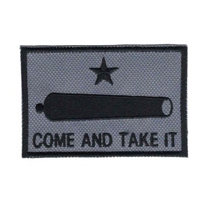 May include: A rectangular patch with a gray background and black border. The patch features a black cannon, a five-pointed star, and the text "COME AND TAKE IT" in black.