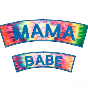 May include: Two tie-dye fabric patches with the words "MAMA" and "BABE" embroidered in blue.