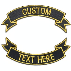 May include: Two black embroidered patches in a banner shape. The top banner reads "CUSTOM" in gold thread, and the bottom banner reads "TEXT HERE" in gold thread. Both patches have gold trim.
