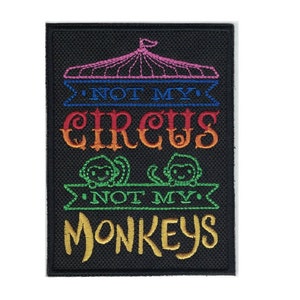 May include: A black embroidered patch with the text "Not My Circus, Not My Monkeys" in rainbow colors. The patch features a pink circus tent and two green monkeys.